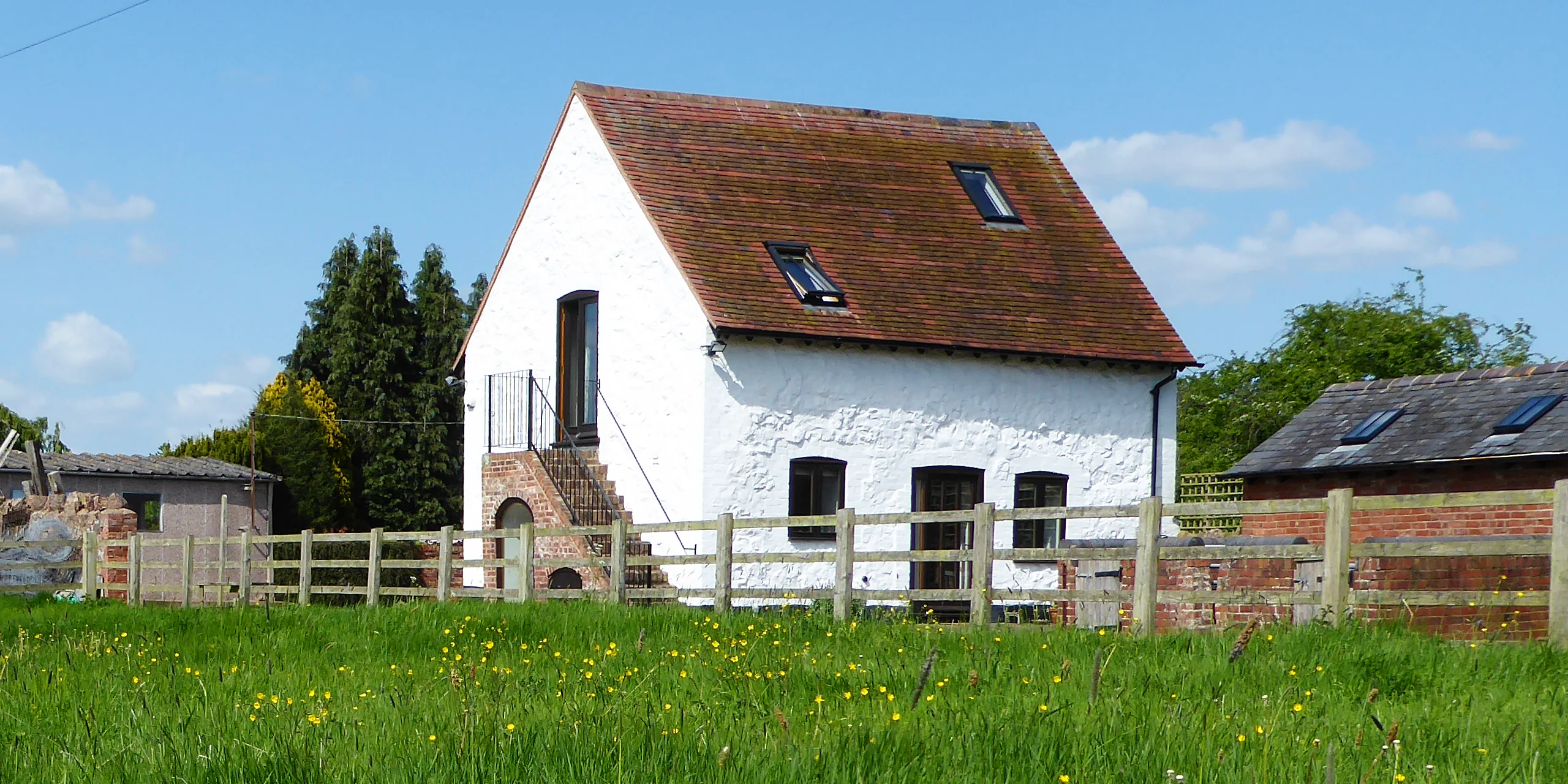 Rhydd Barn from paddock with wild flowers and grasses