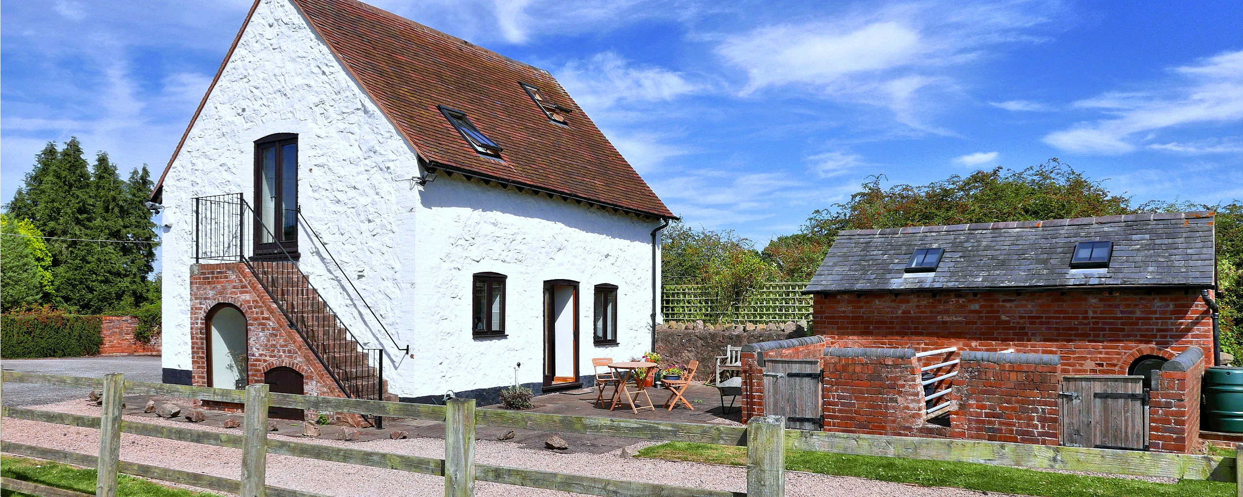 Rhydd Barn's sunny patio with table and chairs and the restored pigsty